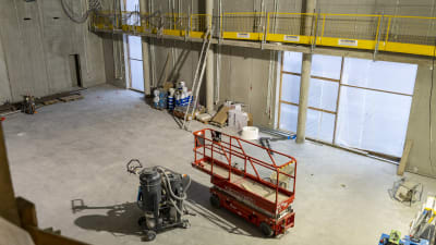 Byggredskap och utrustning står i en stor sal med väggar och golv i betong.