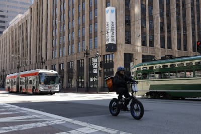 En byggnad med Twitters namn och logotyp. Ett cykelbud, en buss och en spårvagn i förgrunden.
