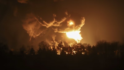 Eldslågor slår upp över trädtoppar vid ett oljeraffinaderi utanför Kiev. 