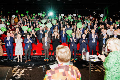 Centerpubliken applåderar efter sin ordförande Annika Saarikkos tal. Många håller också upp gröna pratbubblor i papp.