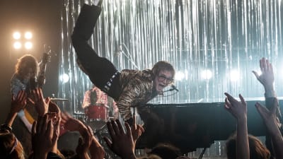 Elton John (Taron Egerton) spelar piano och börjar sväva upp i luften.