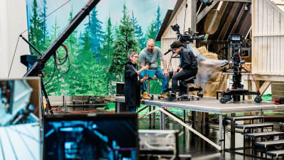 Kolme henkilöä seisoo keskellä television lavasterakennelmaa.