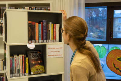 En person väljer böcker från en bokhylla.