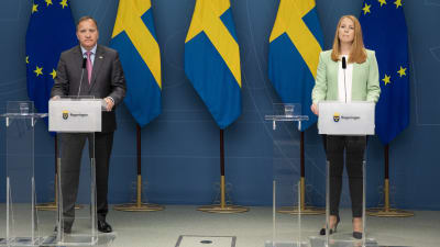 Stefan Löfven och Annie Lööf på pressträff med Sveriges och EU:s flaggor bakom sig.