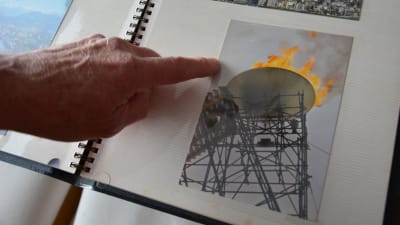Ett finger visar i ett fotoalbum på en bild av den olympiska elden vid de olympiska vinterspelen i Grenoble 1968.