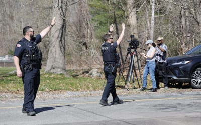 Två poliser gestikulerar med händerna. Två journalister syns i bild.