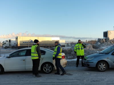 Strejkvakter i gula reflexvästar står framför parkerade långtradare. 