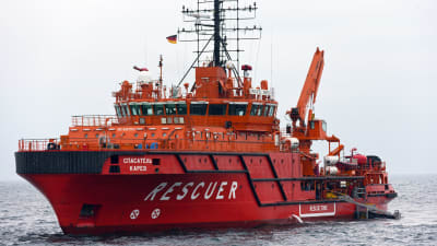 Ett rött-orange färgat fartyg åker på vattnet. På fartyget står det "Spasatel Karev" och "Rescuer".