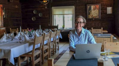 Kvinna sitter bakom en bärbar dator i en restaurang.