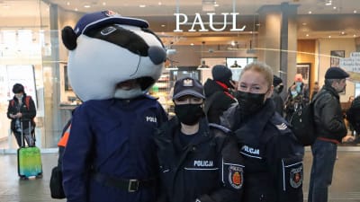 Tre polska poliser. En av dem har satt på sig ett stort leksaksdjurhuvud.