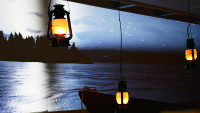 Fotogenlampor lyser. I bakgrunden syns en film där en måne lyser och framför filmduken står en eka.