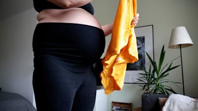 En gravid person viker en handduk.