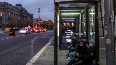 Passagerare i munskydd väntar på en busshållplats i Berlin.