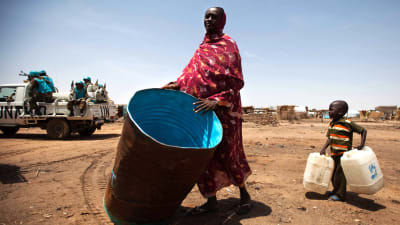 Kvinna bär en vattentank i ett flyktingläger i Sydsudan.