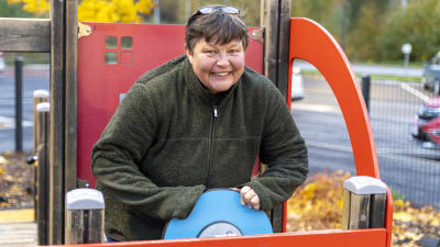 En kvinna i en klätterställning som föreställer en röd bil. Hon finns ute vid daghemmet Karusellen i Karis.