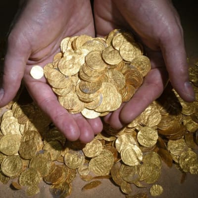 Israeliskt penningfynd på havsbottnen. Två händer håller i en massa gamla mynt. Det ligger också mynt under händerna, i sanden.