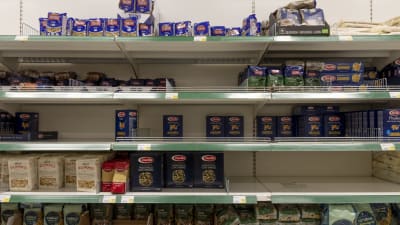 Osin tyhjiä makaronihyllyjä kaupassa.