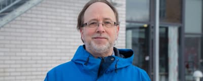 Linus Dolk utomhus framför en byggnad. 