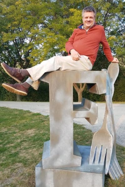 Kettil Cedercreutz poserar på staty föreställande en F-bokstav samt kniv och gaffel.