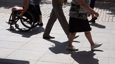 En rullstolsburen person syns bland människor som är ute och går.