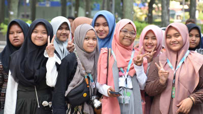En grupp muslimska flickor i Malaysia poserar för kameran och gör segertecken med fingrarna.
