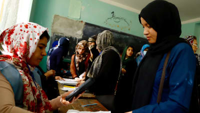 En valfunktionär kontrollerar väljarens identitet i en vallokal i Kabul. 