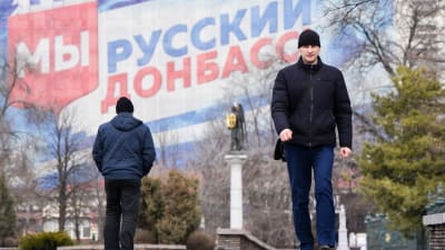 En man poromenerar i bkrgunden syns en väggmålning med texten "Ryska Donbas".
