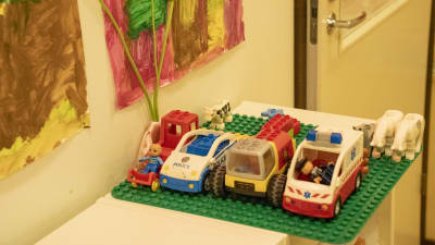 Fyra fordon i lego står uppställda bredvid varandra. De finns på ett daghem.