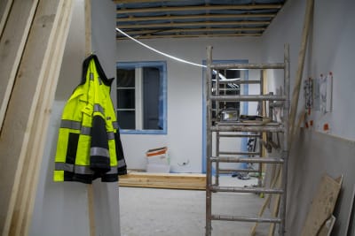 En färggrann arbetsjacka hänger på en spik på ett bygge.