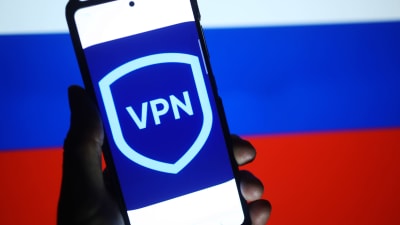 En mobiltelefon där det på skärmen står "VPN". I bakgrunden den ryska flaggan.