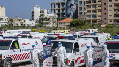 Frivilliga från Hizbollahs civilförsvar visade upp rörelsens ambulanser i mitten av april, i samband med coronakrisen. Bilden är tagen i Tyros, i södra Libanon och i bakgrunden ståtar ett porträtt av Irans andlige ledare Ali Khamenei. 