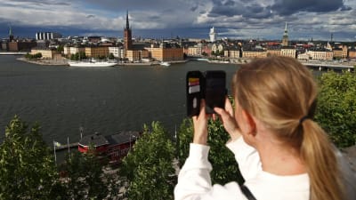 En person tar en bild på Stockholm från Södermalm. I bakgrunden Stockholms skyline.