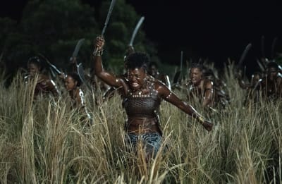 Nanisca (Viola Davis) och hennes armé av kvinnor kommer springande genom högt gräs med machete i händerna.