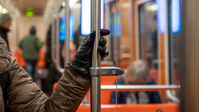 En hand håller i ett räcke i metron.