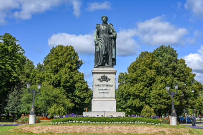 Staty av Karl XIV Johan i en grön park.