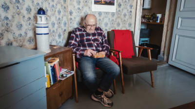 Äldre man sitter i stol och spelar enmansschack. 