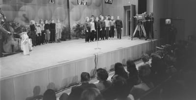 Yleisradion televisiotoiminnan ensimmäinen julkinen televisioitu lähetys "Pikkujoulu on taas" 30.11.1957 Ruotsinkieliseltä kauppakorkeakoululta Helsingistä. Lapsikuoro "Tontut" laulaa, Onni Gideonin yhtye vasemmalla.