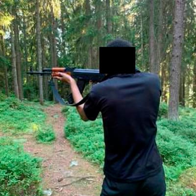 Terrorismirikoksesta syytetty Suomessa asuva espanjalaismies aseen kanssa ensin sisätilassa, toisessa kuvassa metsässä, kasvot peitettyinä eli tunnistamattomana.