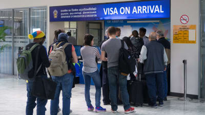 Turister på flygplats köar för att skaffa visum.