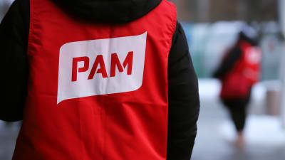 En person som har ryggen mot kameran som bär en röd väst med servicefacket Pams logo.