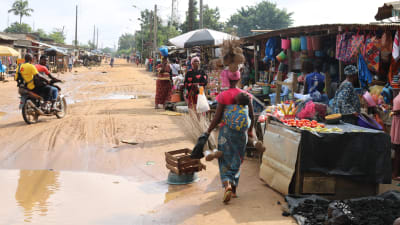 Sandväg kantad av marknadsstånd i det fattiga området Abobo i Elfenbenskusten.