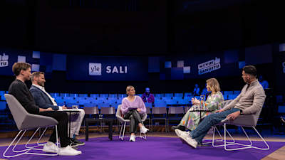 Lavalla Milla Madetoja ja vieressä vieraat istumassa.