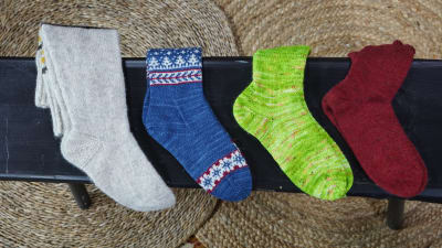 Neljä käsinkudottuja sukkia eri väreissä.