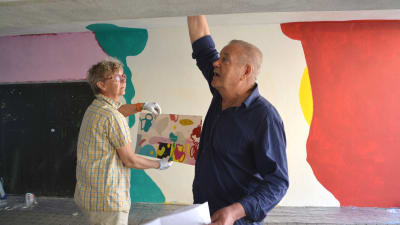Konstnärerna arbetar i tunneln, Ylva håller en skiss över hur väggen ska se ut: grönt, rött, gult ska det bli.