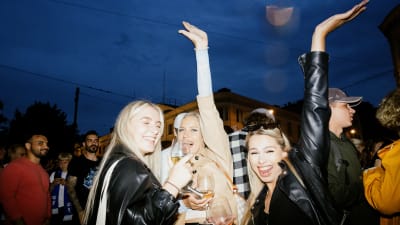 Tre kvinnor firar fotbollsherrarnas vinst. De posterar med händerna i luften.
