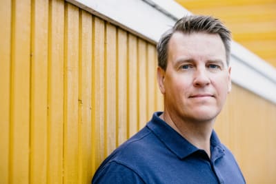 Nordnets ekonomiska expert Martin Paasi står lutad mot en gul vägg.