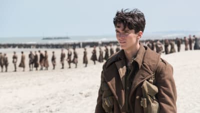 Tommy (Fionn Whitehead) står på stranden tillsammans med en massa andra soldater. 