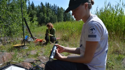 Roosa Mikkola visar upp en av de många utrustningar som hon och Ella Pippingsköld har med sig. Saken som Mikkola har i handen mäter de flesta värden man kan ta av ett vattendrag.