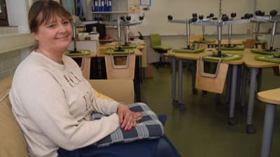En kvinna sitter på en soffa i ett klassrum. Hon heter Anu Hausen och är rektor för Päivärinteen koulu i Sjundeå.
