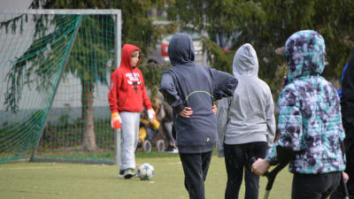 Vårberga skolas elever spelar fotboll i en hagelskur.
